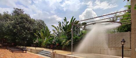 A wooden deck with lounge chairs, a water feature, and a brick wall with a sign.