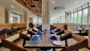 A spacious dining area with high ceilings, large windows, and modern furniture. - Pushpam sanskruti Resort (Karjat)