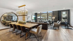Een moderne woonkamer met een houten eettafel, leren banken en een grote spiegel.