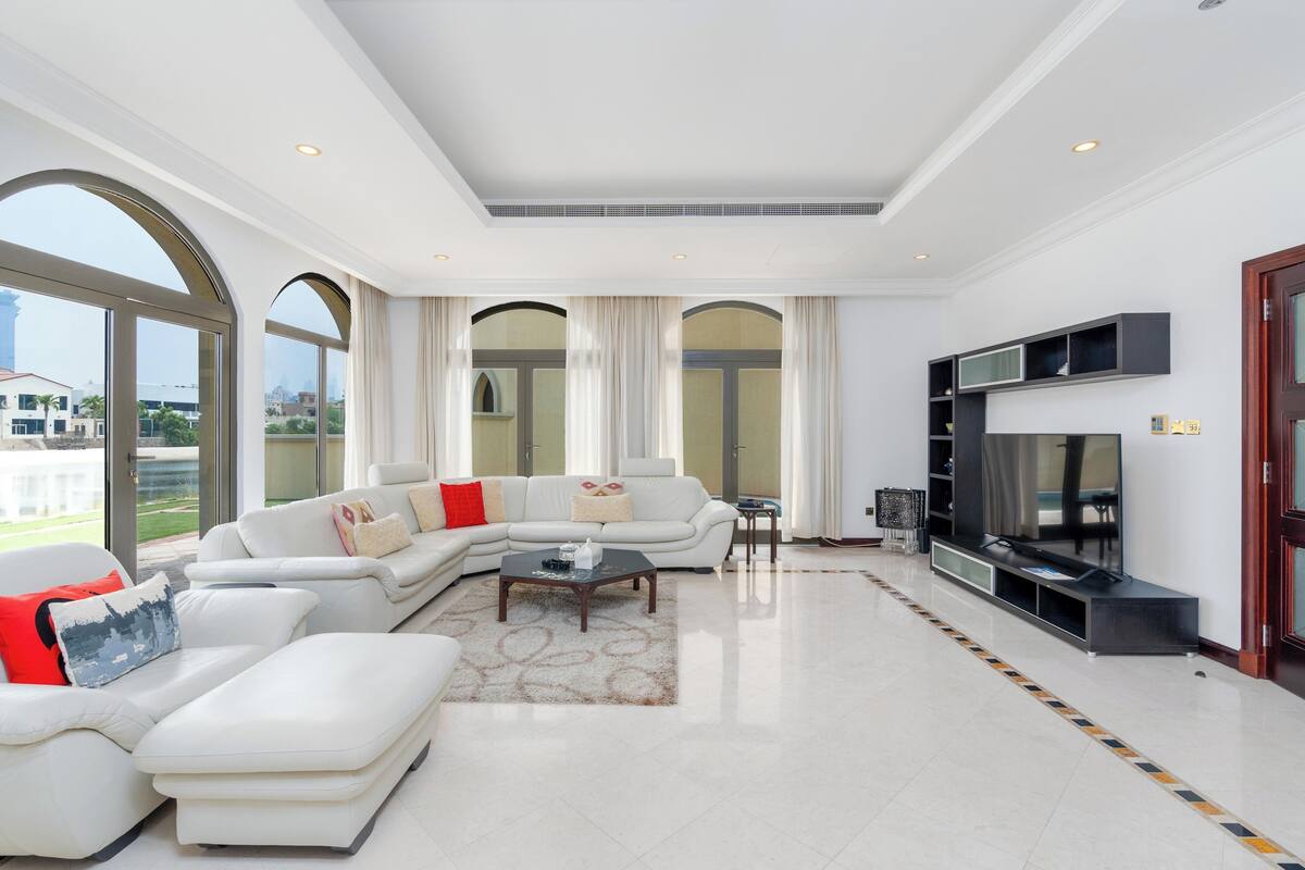 A spacious living room with a sectional sofa, a coffee table, and a flat-screen TV.