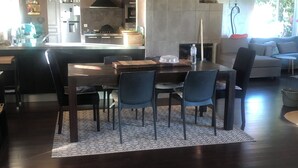 Una sala de estar moderna con comedor, que presenta pisos de madera oscura, un tapete estampado y muebles contemporáneos.