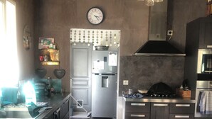 Una cocina moderna con un refrigerador de acero inoxidable, una estufa a gas y un reloj en la pared.