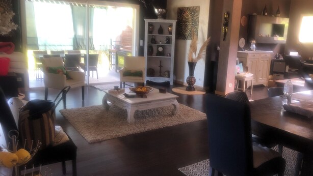 Un salón amplio con un ventanal grande, un comedor con mesa y sillas, y una cocina con armarios y encimera.