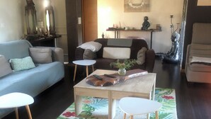 Sala de estar con sofá, una mesa de centro, sillas, una mesita auxiliar, un tapete decorativo y una estatua de Buda.