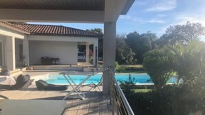 Zona junto a la piscina con sillones de descanso y vistas a una piscina.