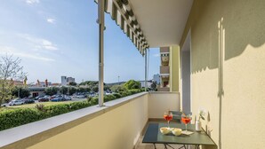 Ein Balkon mit Tisch und Stühlen und Blick auf einen Parkplatz sowie ein Gebäude im Hintergrund.
