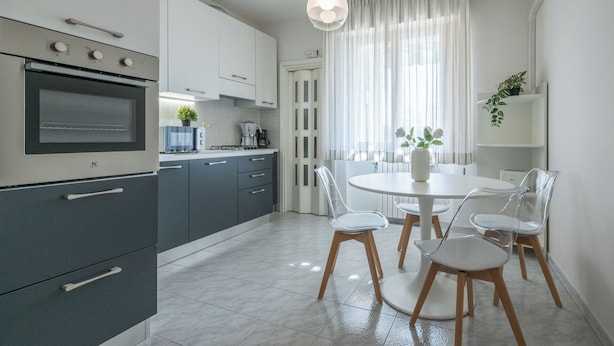 Eine moderne Küche mit Einbauofen, Kaffeemaschine und Essbereich mit rundem Tisch und vier Stühlen.