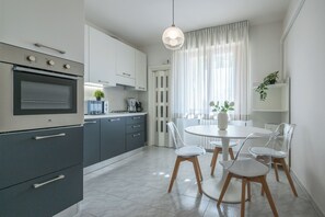 Una cocina moderna con horno empotrado, cafetera y comedor con mesa redonda y cuatro sillas.
