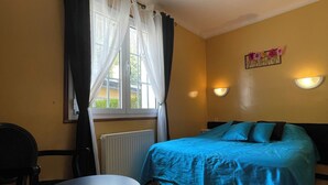 Une pièce comprenant un lit, une table, une chaise, une fenêtre avec des rideaux et des lampes fixées au mur.