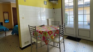 Un coin repas avec une table recouverte d’une nappe colorée, entourée de chaises en métal.