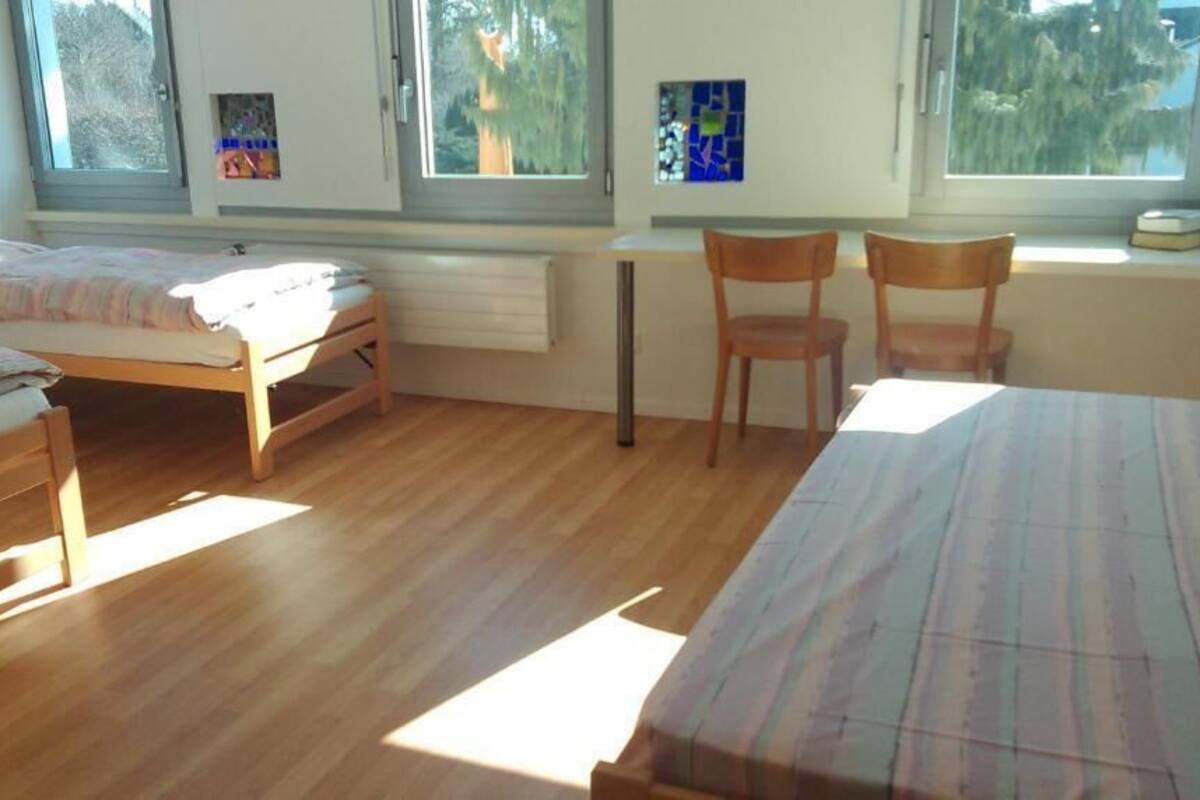 A bedroom with two beds, a desk, and a chair.