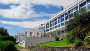 A modern building with a long, straight facade, large windows, and a stone retaining wall. - Centre St-François (Delémont)