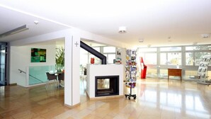 A spacious living area with a fireplace, a bookshelf, and a glass partition. - Centre St-François (Delémont)