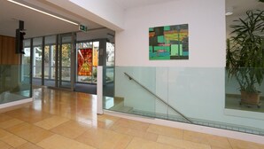 A modern interior with glass doors, a staircase, and a colorful abstract painting. - Centre St-François (Delémont)