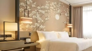 Ein Hotelzimmer mit Bett, Nachttischlampen, einem Schreibtisch und einer Wand mit floralem Wandbild.