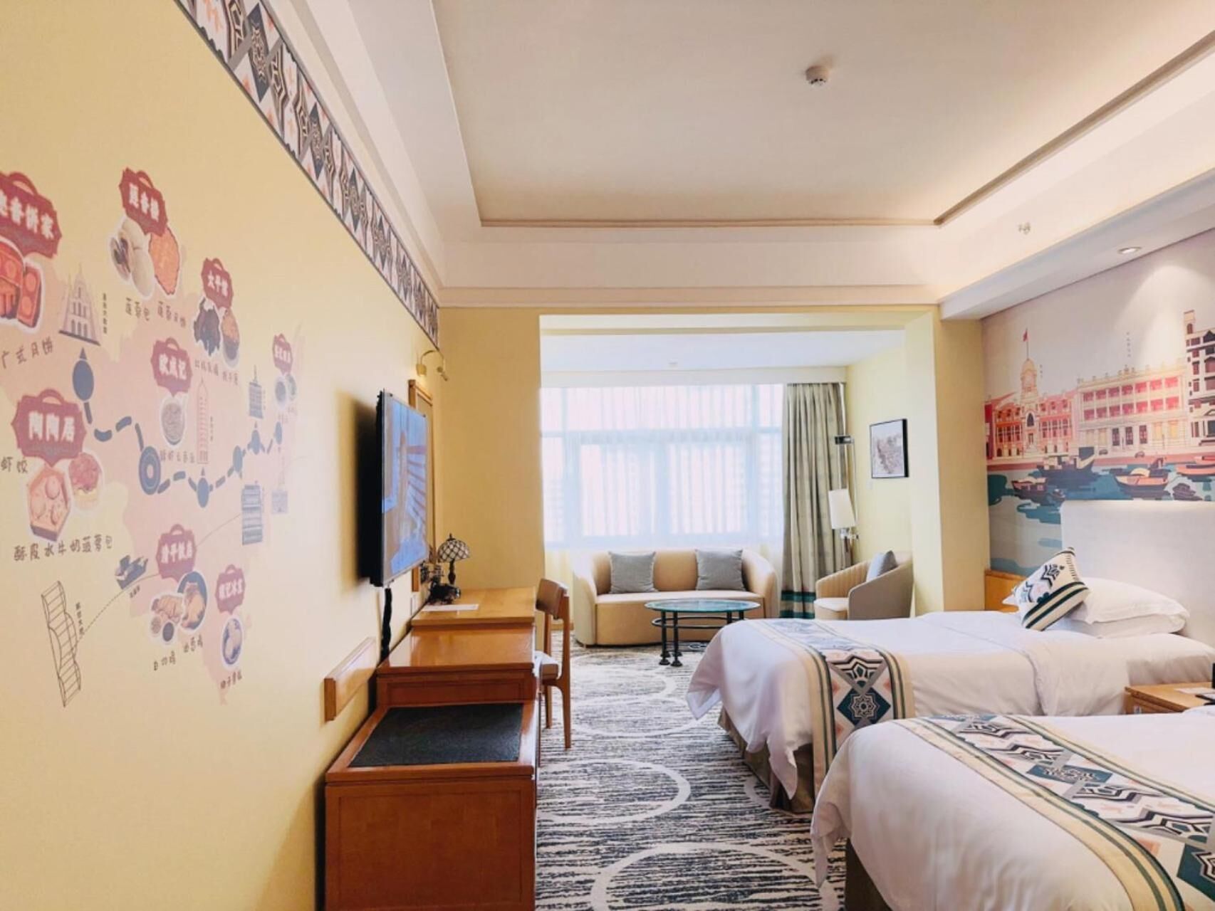 A hotel room with a bed, a desk, a chair, a TV, and a wall with a cityscape mural.