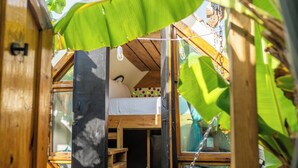 A compact, wooden room with a bunk bed, a small shelf, and a window.