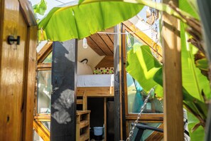 Une petite pièce en bois, avec un lit superposé, une petite étagère et une fenêtre.