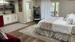 Un dormitorio con cama, mesita de noche, ventana con cortinas, ventilador de techo y vistas al exterior.