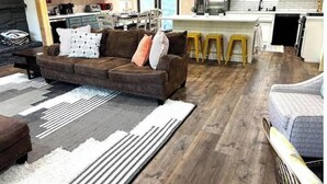 Una cocina moderna con armarios blancos, una isla central y una zona de comedor con mesa y sillas.