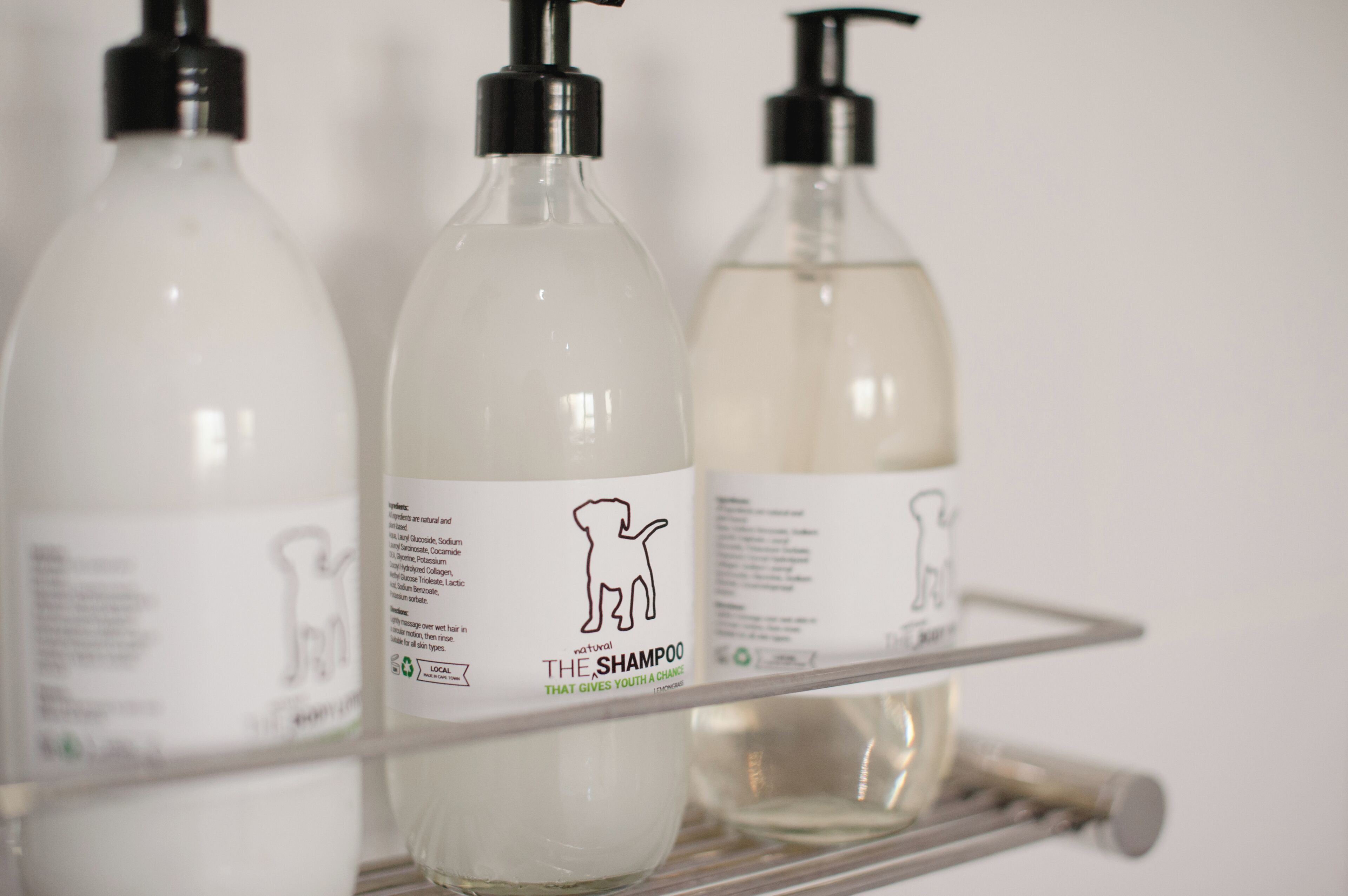 Trois bouteilles de shampoing sur une étagère.
