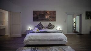 Een slaapkamer met een groot bed, een schilderij van een leeuw en twee nachtkastjes met lampen.