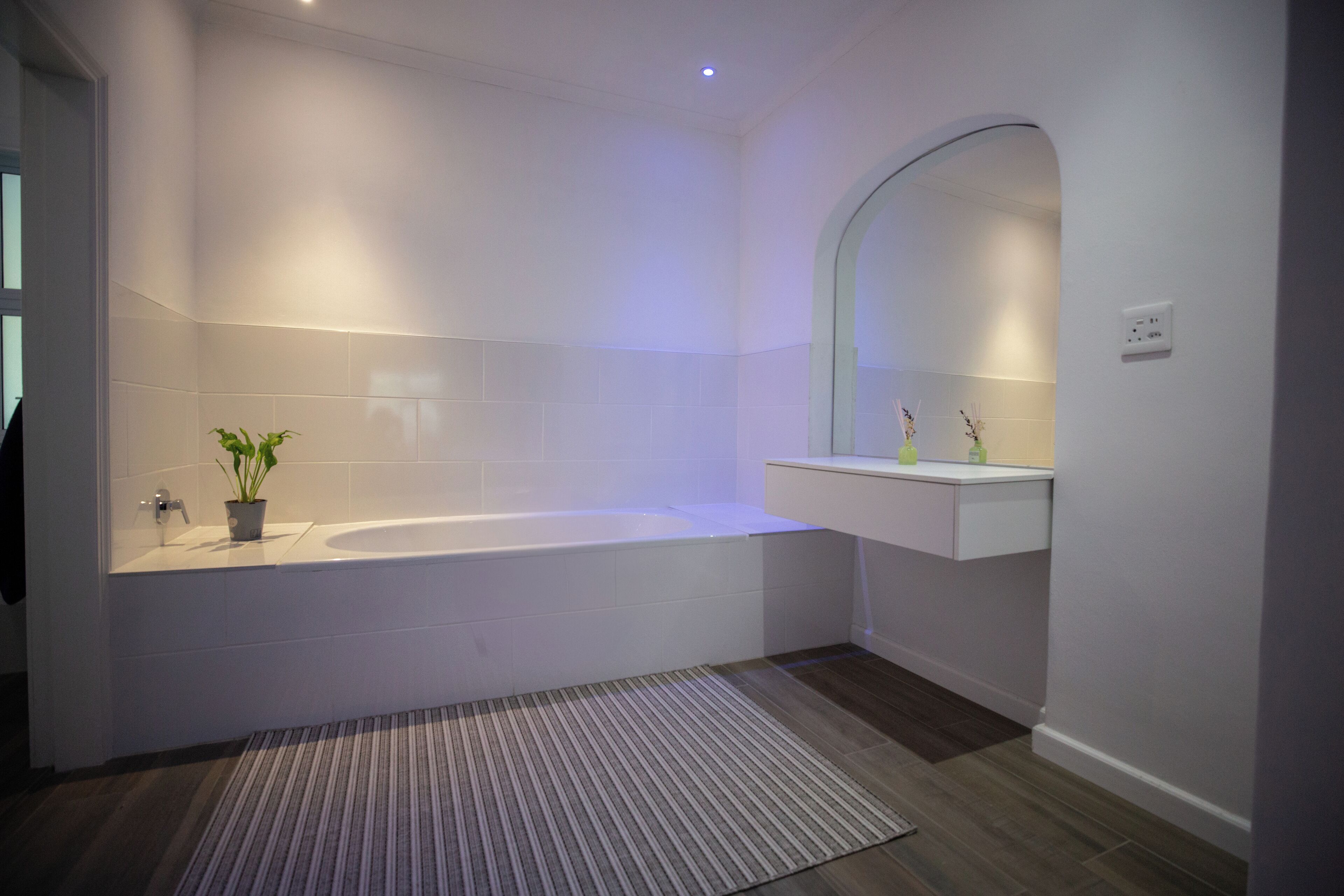A modern bathroom with a bathtub, a sink with a mirror, and a potted plant.