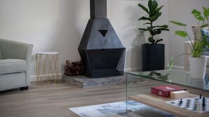Een moderne woonkamer met een open haard, een bank, een salontafel en een boekenkast.