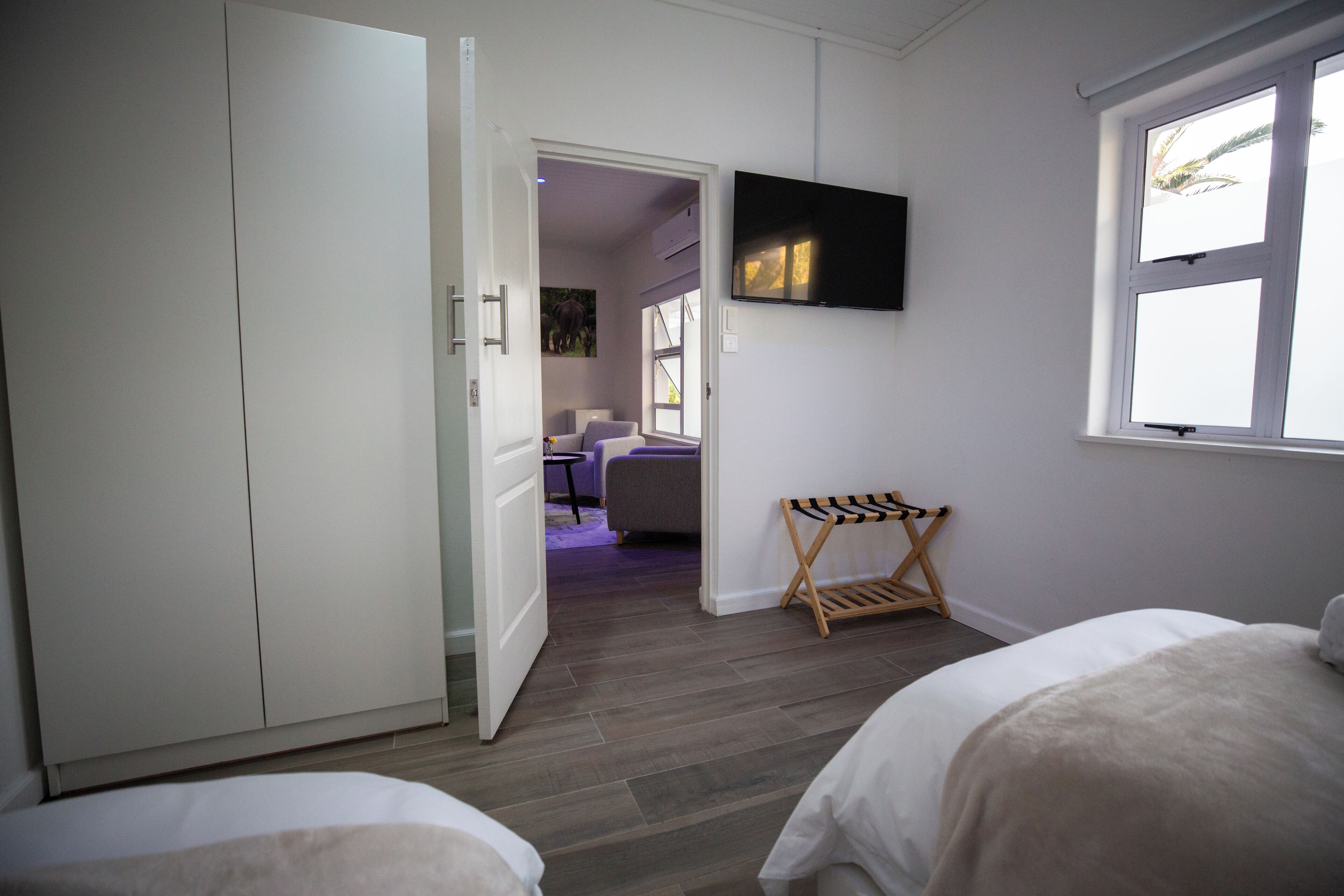 A bedroom with a bed, a wardrobe, a TV mounted on the wall, and a window.