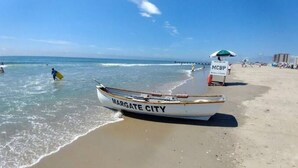 Une plage avec un bateau portant l’inscription « MARGATE CITY » et un panneau indiquant la présence d’un sauveteur.