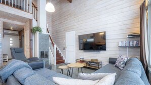 Un salon moderne avec un canapé gris, un téléviseur à écran plat et un escalier menant à un niveau supérieur.