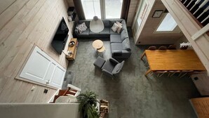 Un intérieur moderne avec un canapé d’angle gris, une table basse ronde et une table à manger en bois.