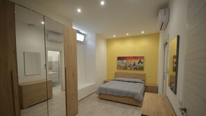 A bedroom with a bed, a bedside table, a mirror, and a painting on the wall. - SanRemo Apartment (Roma)