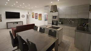 A modern kitchen with a central island, built-in oven, microwave, and a large flat-screen TV mounted on the wall. - SanRemo Apartment (Roma)