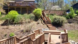 Ein zweistöckiges Haus mit einer Holzterrasse und einer Treppe zu einem überdachten Bereich.