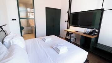 Una habitación de hotel con una cama, un escritorio, un televisor y una puerta que da a un baño.