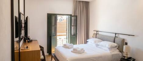 Habitación de hotel con cama, escritorio, sillón, sofá y vistas al exterior.