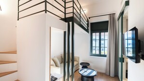 Un interior moderno con una escalera, un sofá, una mesa de centro y un televisor.