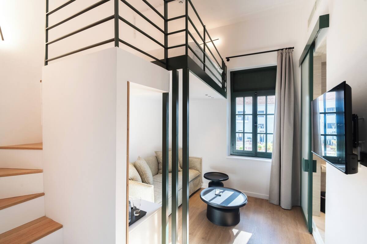 A modern interior with a staircase, a sofa, a coffee table, and a TV.
