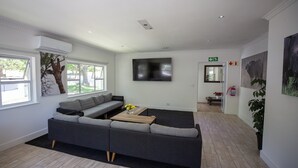 Een moderne woonkamer met een hoekbank, een flatscreen televisie en een salontafel met bloemen.