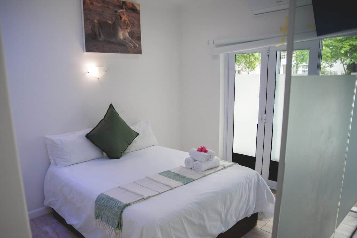 A bedroom with a bed, pillows, a blanket, and a painting on the wall.