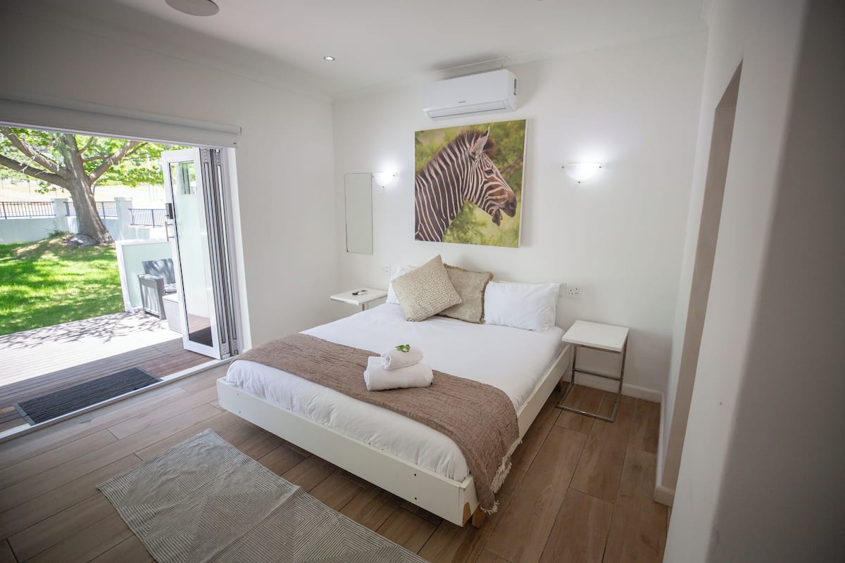 A bedroom with a large bed, a zebra painting, and a sliding glass door leading to an outdoor area.