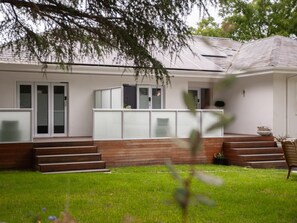 Una casa moderna con un porche delantero, una escalera que conduce a la entrada y un pequeño jardín.