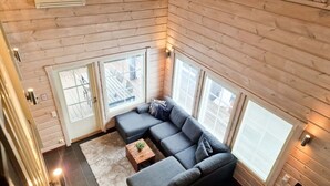 A modern loft-style room with a sectional sofa, a small wooden coffee table, and large windows providing natural light. - Villa Tähkä, HimosYkkösen alue (Keski-Suomi)