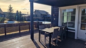 A covered outdoor deck with a table and chairs, overlooking a snowy landscape and neighboring houses. - Villa Tähkä, HimosYkkösen alue (Keski-Suomi)