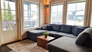 A cozy living room with a sectional sofa, a small wooden coffee table with a plant, and large windows offering a view of the outdoors. - Villa Tähkä, HimosYkkösen alue (Keski-Suomi)