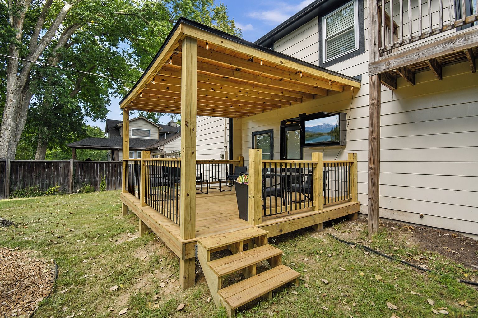 Une terrasse en bois avec une pergola, un espace salon extérieur et une vue sur un lac.