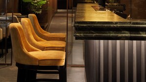 A reception area with a bar, seating, and decorative plants. - U-Visionary Venezia Hotel (Venice)