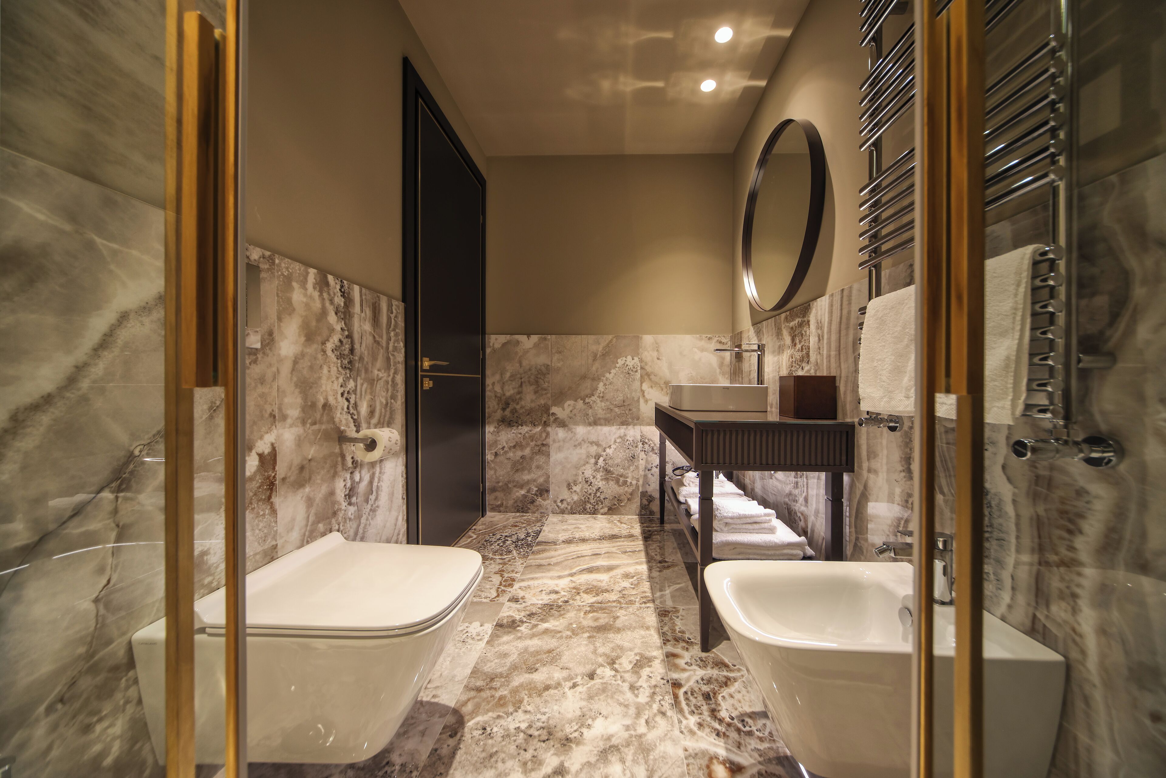 Un baño moderno con dos lavamanos separados, un espejo grande y cabina de ducha con paredes de cristal.