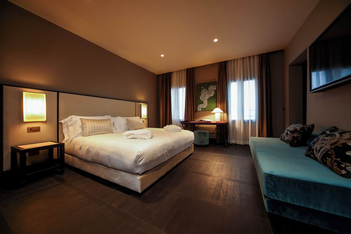 Een hotelkamer met een groot bed, een bureau, een bank en een schilderij aan de muur.